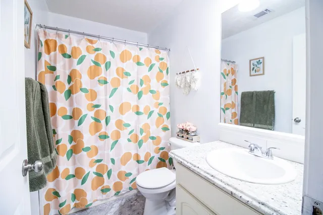 a bathroom with a granite countertop toilet a sink and a mirror