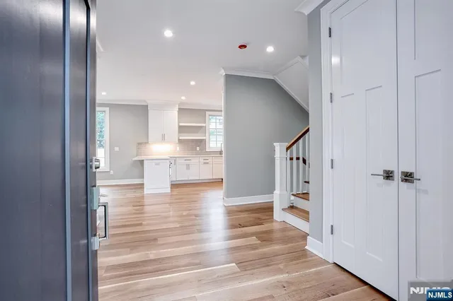a view of a hallway with wooden floor cabinets and a kitchen