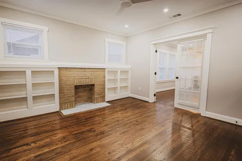 a view of empty room with wooden floor and fireplace