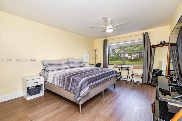 a bedroom with a bed wooden floor and a large window