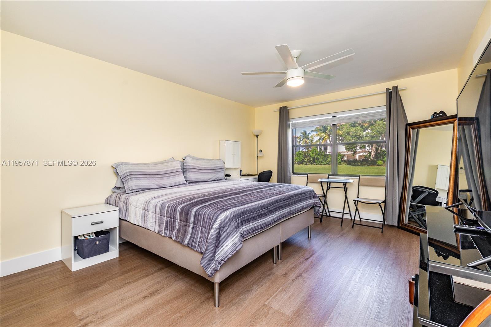 9355 Southwest 8th Street, Unit 105 Boca Raton, FL 33428 - Photo 18 of 37 a bedroom with a bed wooden floor and a large window
