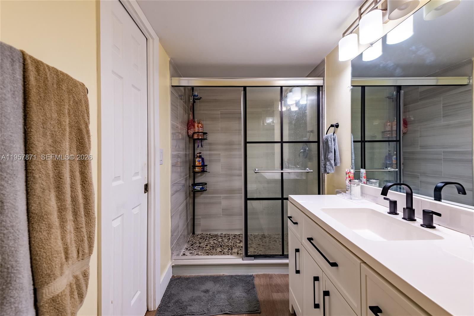 9355 Southwest 8th Street, Unit 105 Boca Raton, FL 33428 - Photo 21 of 37 a bathroom with a double vanity sink a mirror and shower