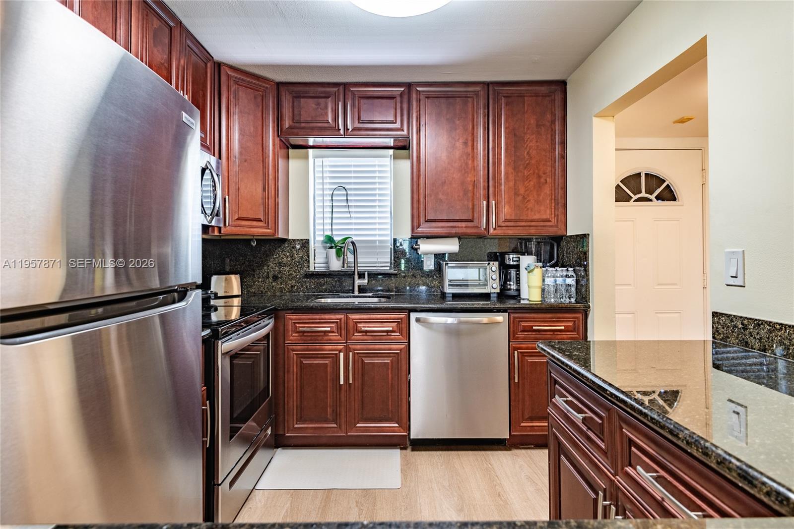 9355 Southwest 8th Street, Unit 105 Boca Raton, FL 33428 - Photo 4 of 37 a kitchen with stainless steel appliances granite countertop a refrigerator a sink dishwasher a stove and white countertops with wooden floor