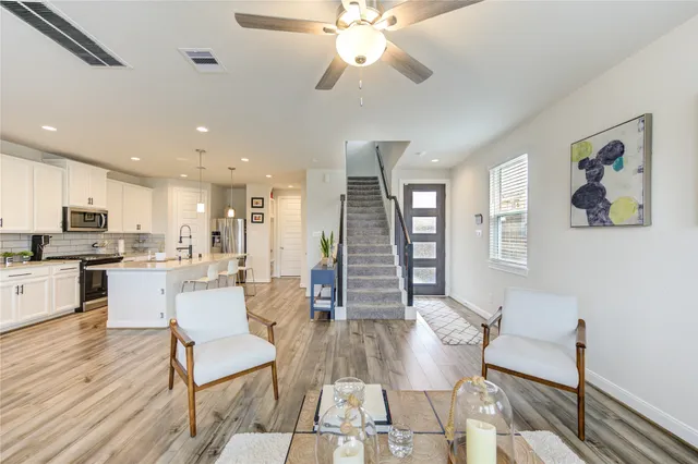 a living room with dining room couches and kitchen view with wooden floor