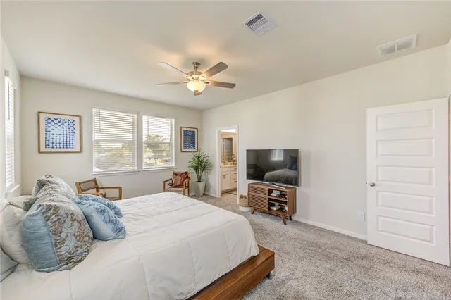 a bedroom with a large bed a flat tv screen and a dresser