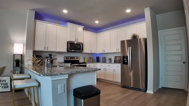 a kitchen with granite countertop a refrigerator stove and microwave