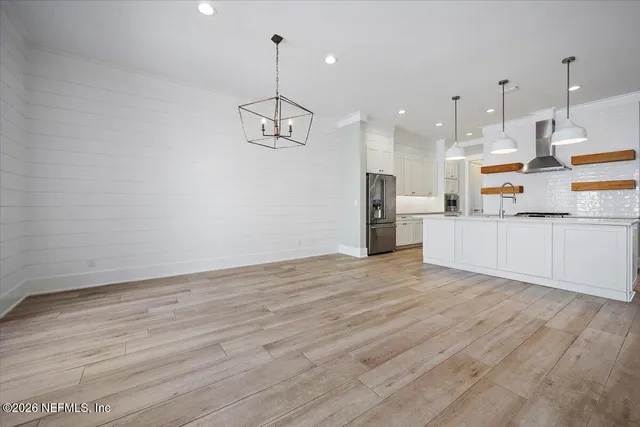 a kitchen with stainless steel appliances granite countertop a sink a stove a refrigerator and a wooden floor