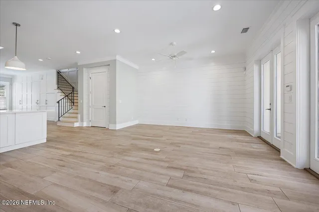 a view of an empty room with kitchen and window