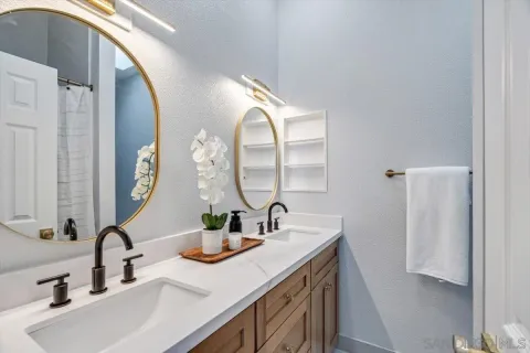 a bathroom with double vanity sink and two mirror