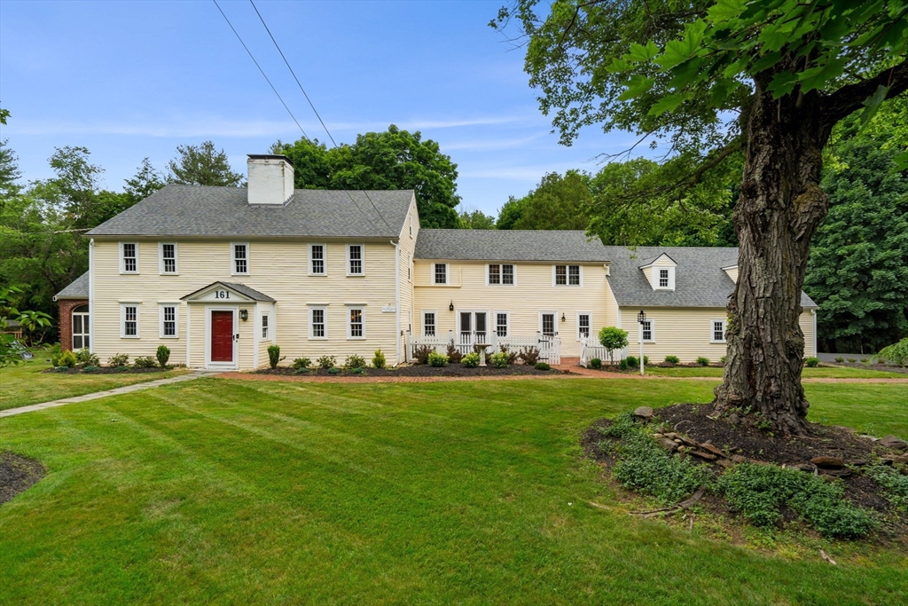a view of a big house with a big yard and large trees