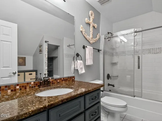 a bathroom with a granite countertop sink toilet mirror and shower