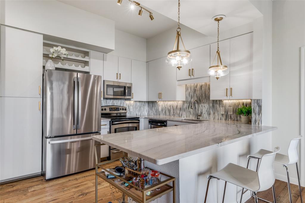 3225 Turtle Creek, Unit 719 Dallas, TX 75219 - Photo 5 of 24 a kitchen with granite countertop a table chairs stainless steel appliances and wooden floor