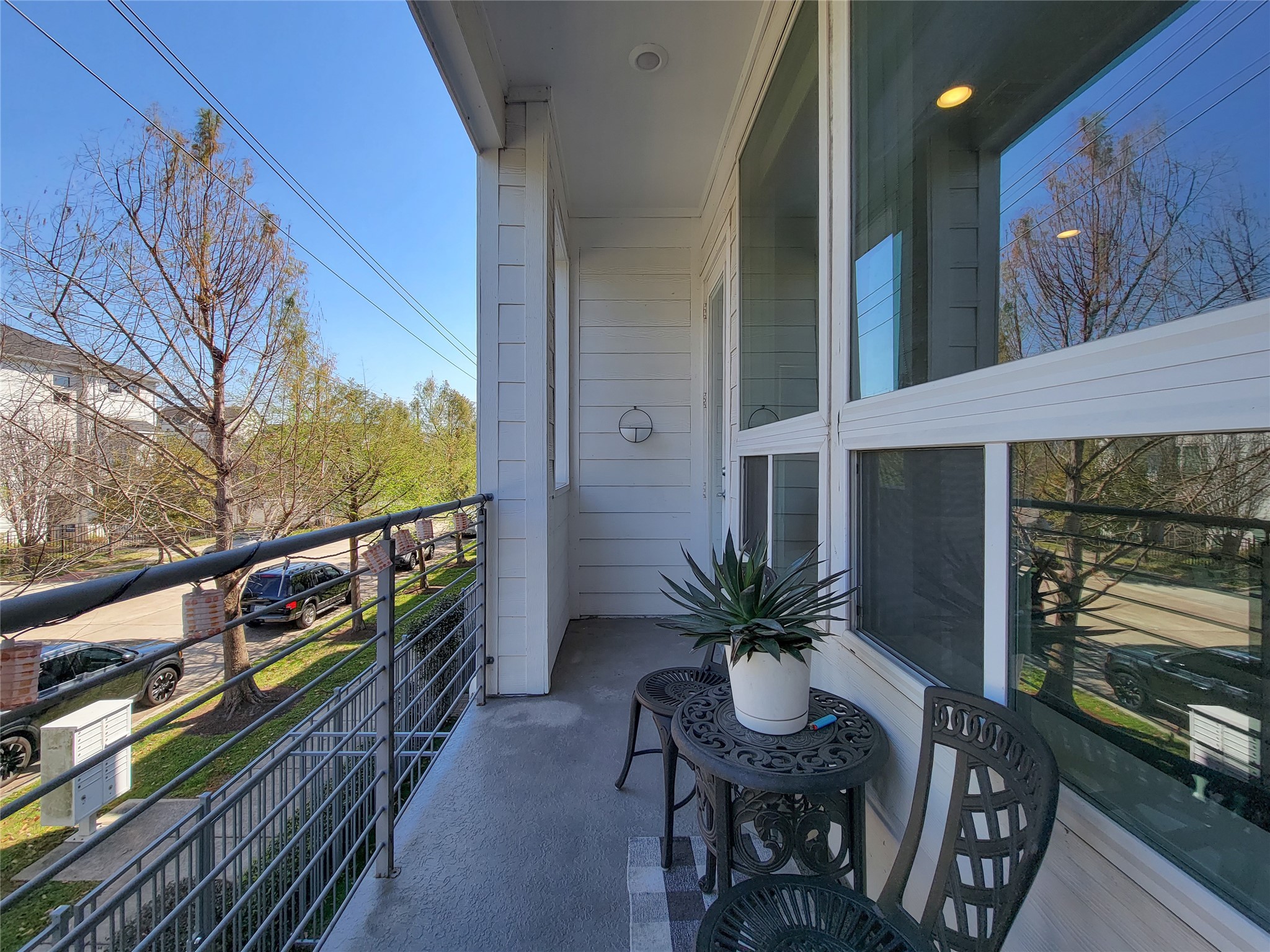 1705 Eado Point Lane Houston, TX 77003 - Photo 36 of 50 The cozy balcony can accommodate a small table and chairs, ideal for relaxing. The view includes a tree-lined street, offering a pleasant outdoor space with a touch of greenery.