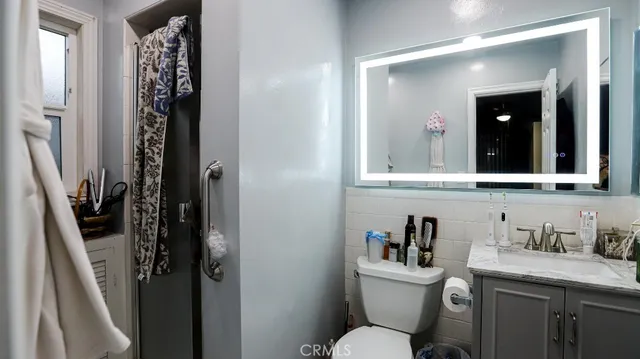 a bathroom with a granite countertop sink toilet and mirror