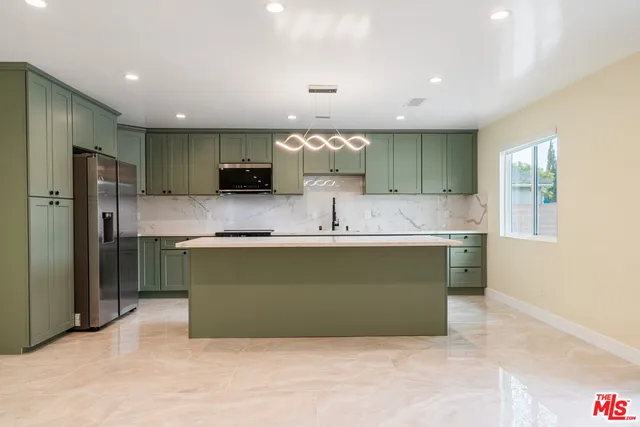 a kitchen with kitchen island granite countertop a refrigerator and a sink
