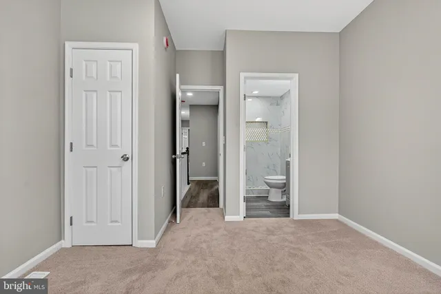 a view of a bathroom with a walk in closet and wooden floor