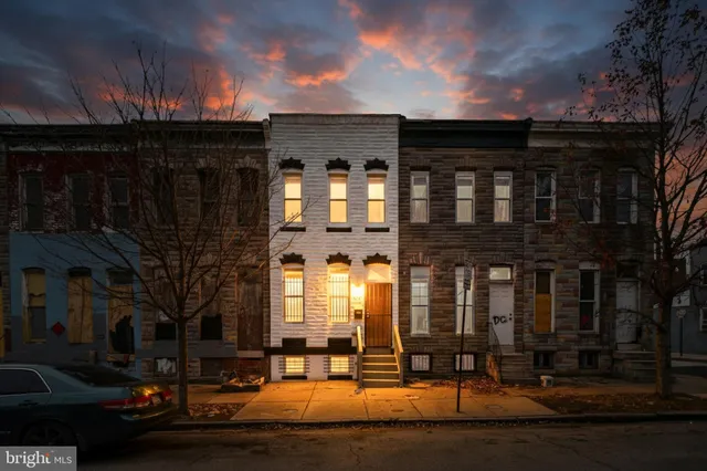 a front view of a building with lot of cars and trees
