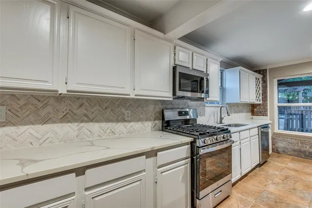 a kitchen with stainless steel appliances granite countertop a stove a sink and a microwave