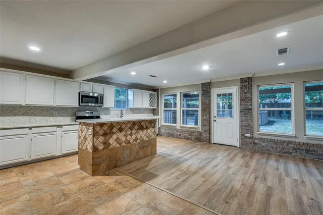 a large kitchen with stainless steel appliances granite countertop a large window a oven and a sink with granite countertops