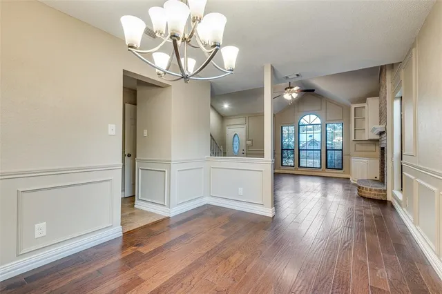 a view of a hallway with wooden floor and chandelier