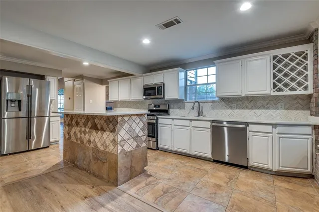 a kitchen with granite countertop a refrigerator oven a sink dishwasher and white cabinets with wooden floor