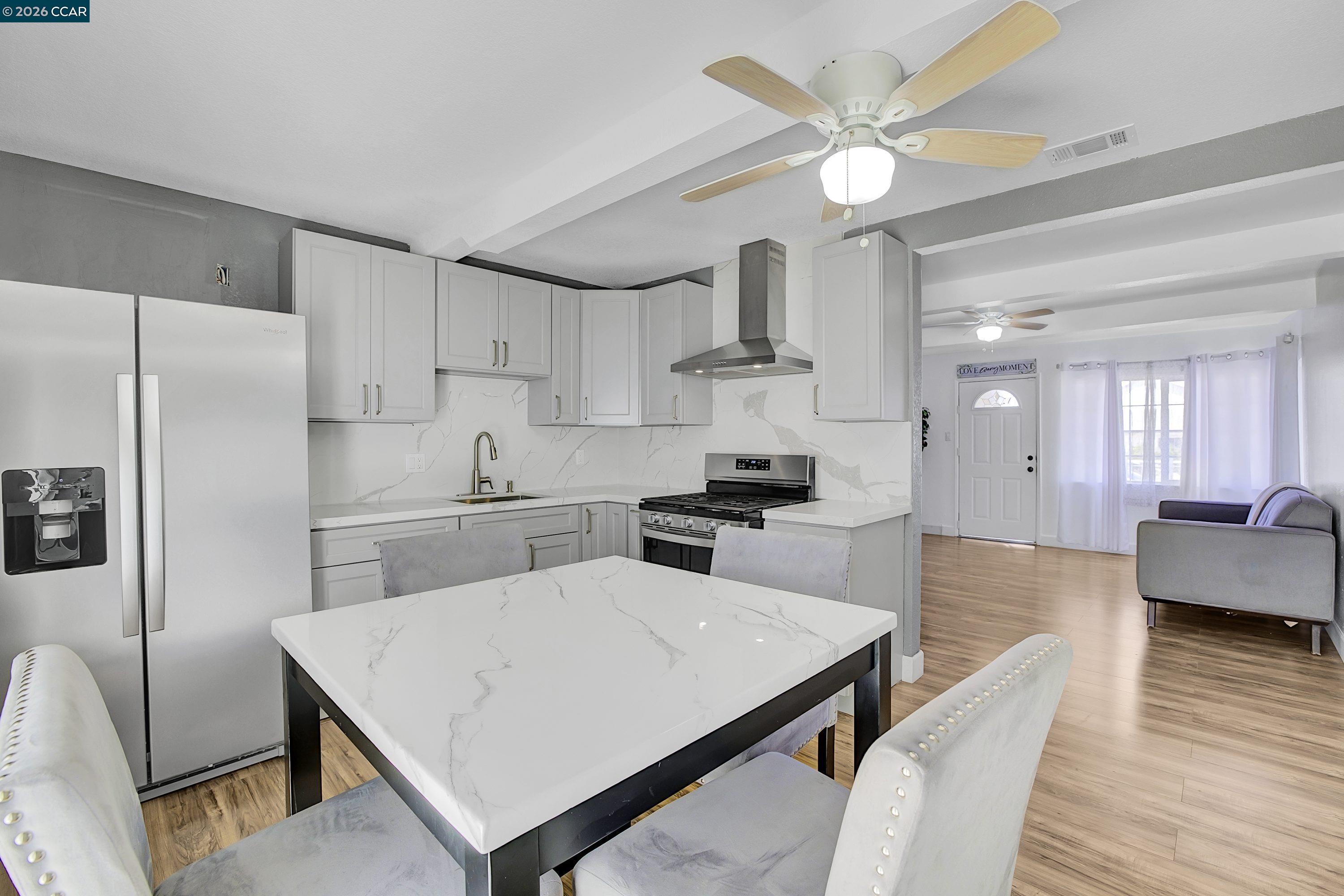 a kitchen with stainless steel appliances a stove a refrigerator a sink dishwasher and white cabinets with wooden floor