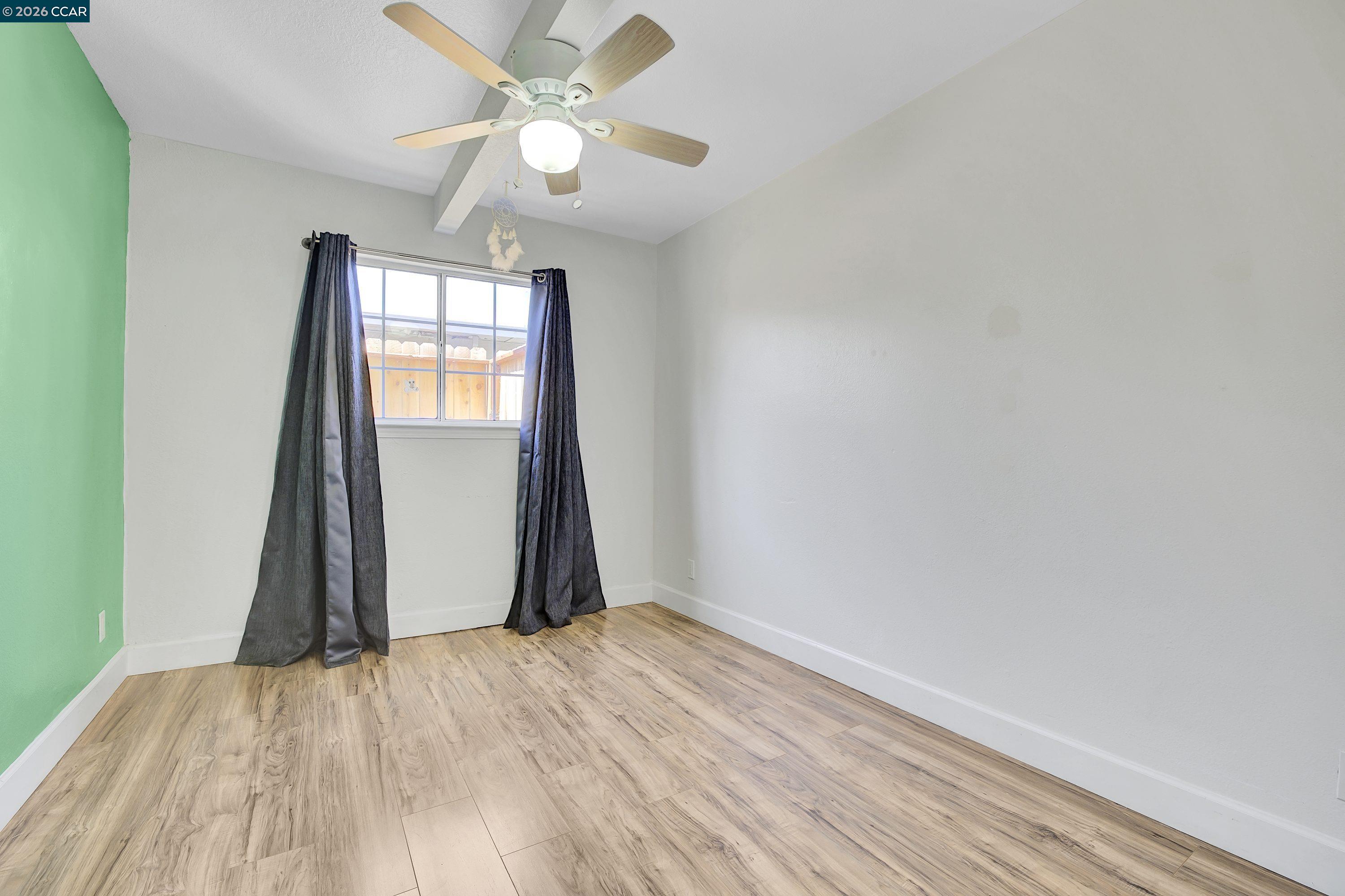 149 Shore Road Bay Point, CA 94565 - Photo 10 of 30 an empty room with wooden floor chandelier fan and windows