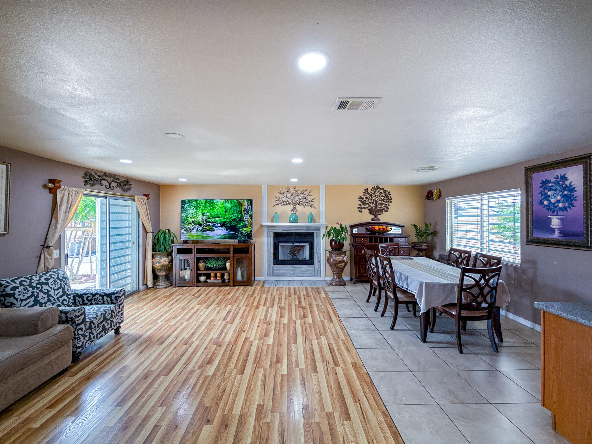 45431 Sancroft Avenue Lancaster, CA 93535 - Photo 23 of 49 a living room with furniture a fireplace and a dining table with wooden floor