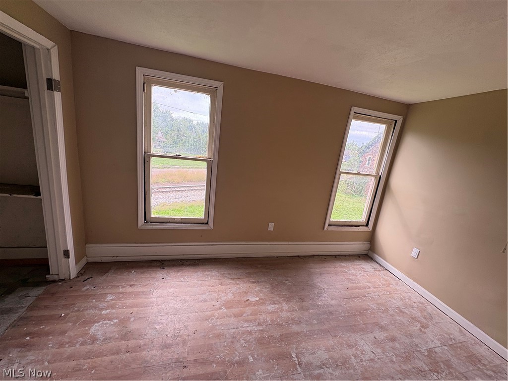 1210 Lawrence Road Northeast Canton, OH 44705 - Photo 32 of 38 Two vertical windows, sloped ceiling, light-toned wall paint, white trim, and a built-in closet with shelving
