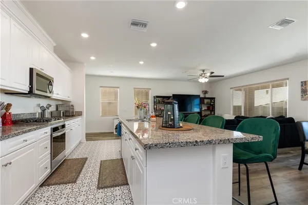 a kitchen with granite countertop kitchen island stainless steel appliances a sink stove and cabinets