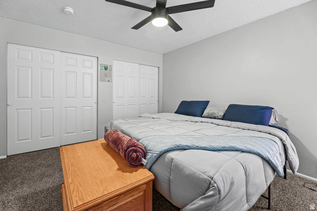 5896 South 3950th Street West Roy, UT 84067 - Photo 11 of 29 Carpeted bedroom with two closets, a textured ceiling, and a ceiling fan