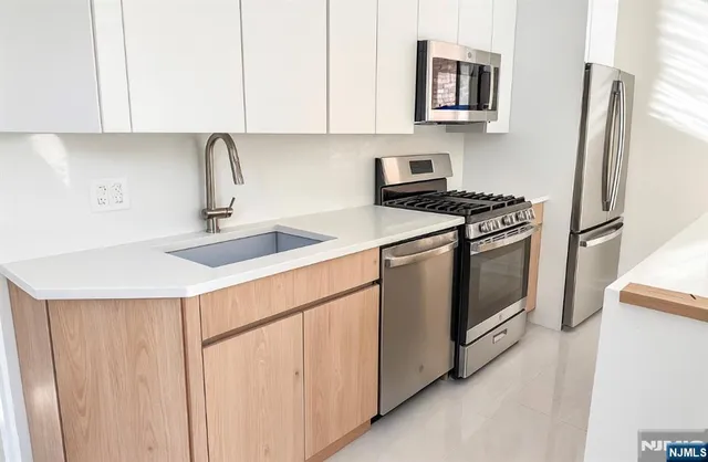 a kitchen with stainless steel appliances a refrigerator a sink a stove and cabinets
