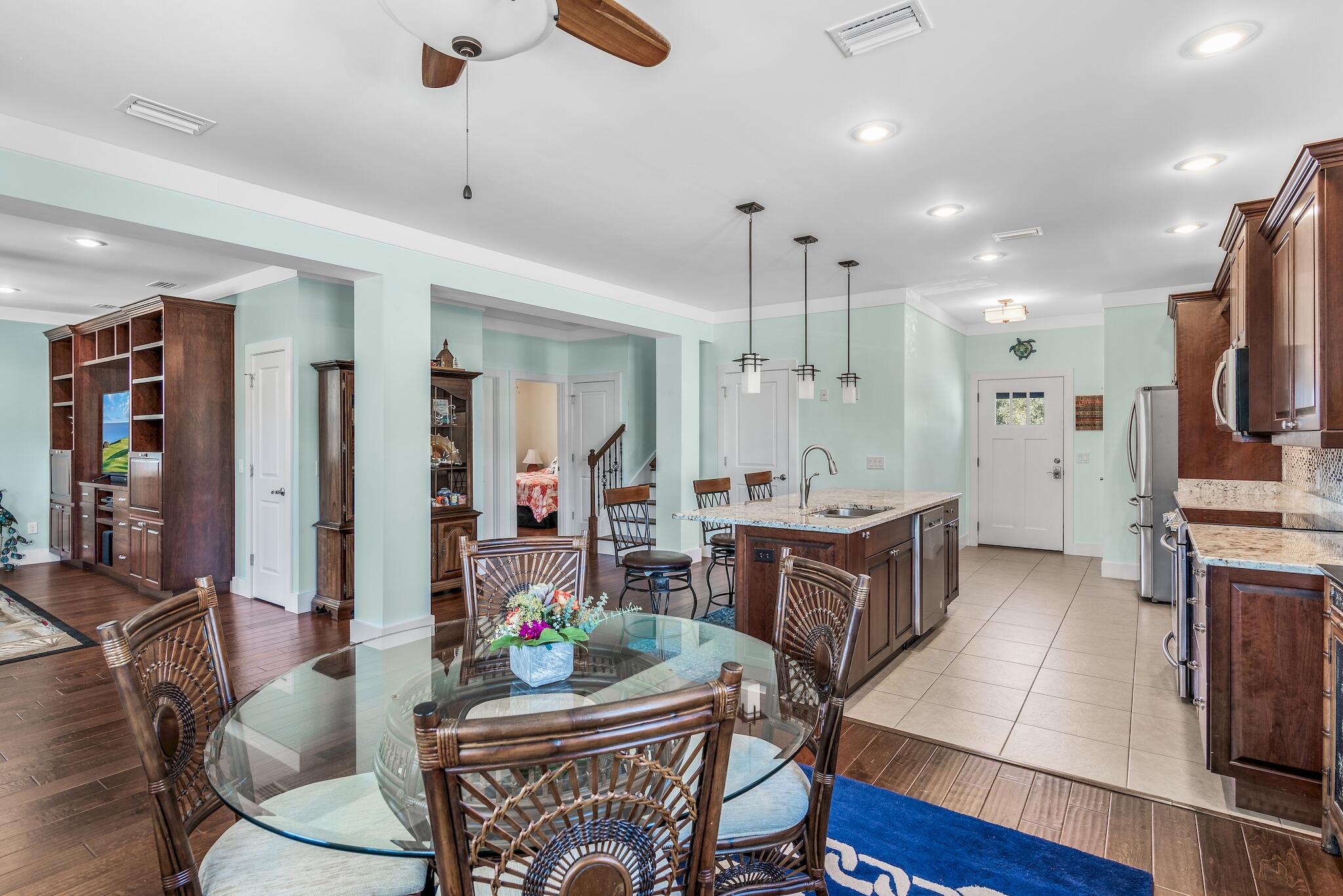 225 Turtle Cove Panama City Beach, FL 32413 - Photo 12 of 43 a large kitchen with stainless steel appliances kitchen island granite countertop a refrigerator a stove a sink a dining table and chairs with wooden floor