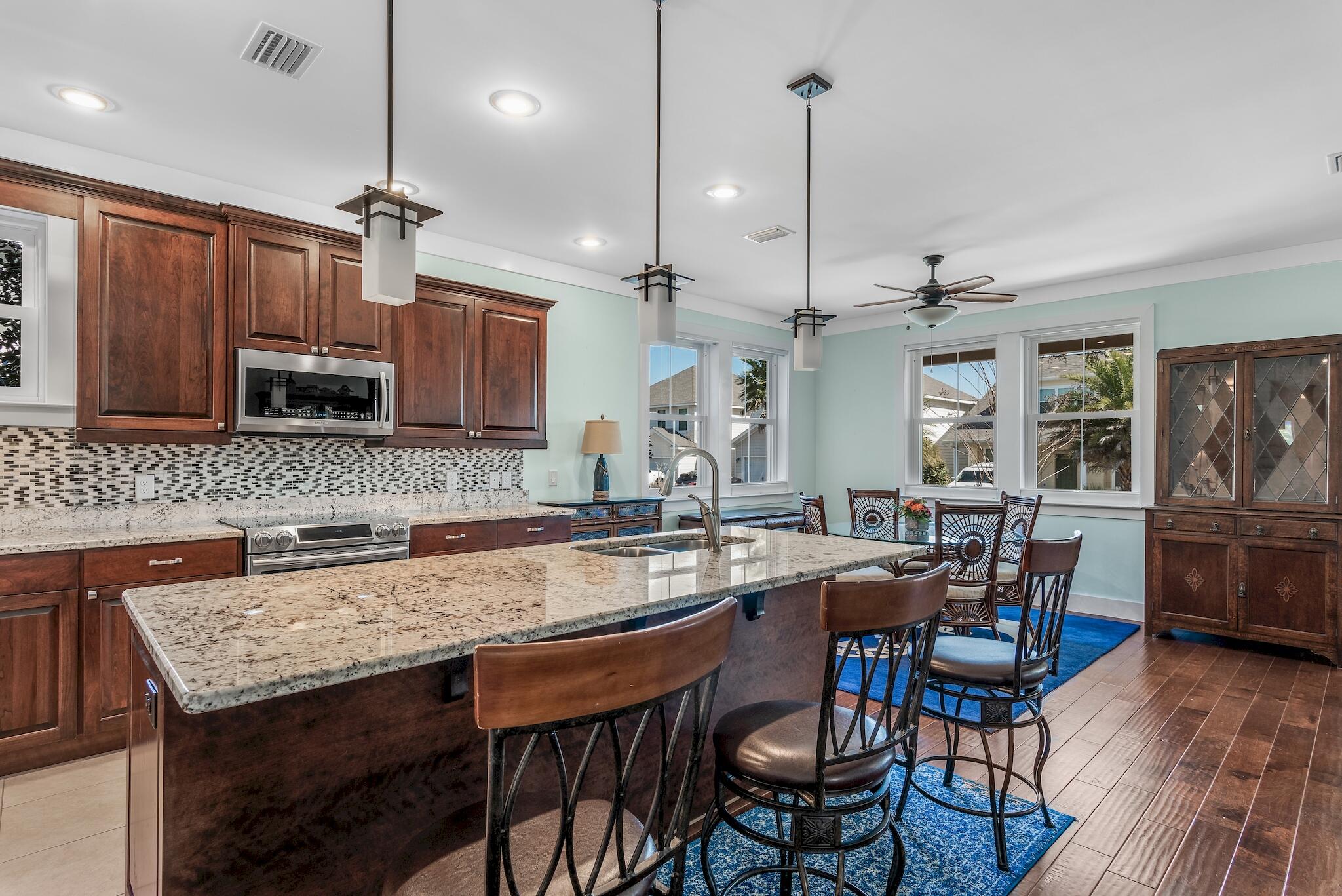 225 Turtle Cove Panama City Beach, FL 32413 - Photo 9 of 43 a kitchen with granite countertop a stove a sink a dining table and chairs