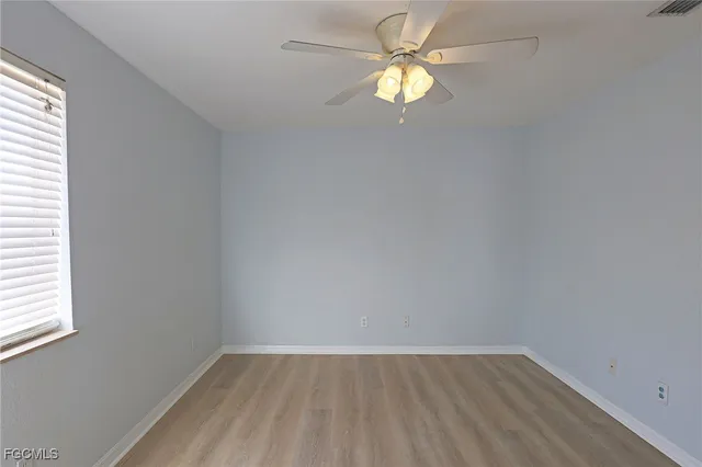 an empty room with a window and a fan