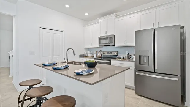 a kitchen with stainless steel appliances granite countertop a refrigerator a stove a sink and white cabinets