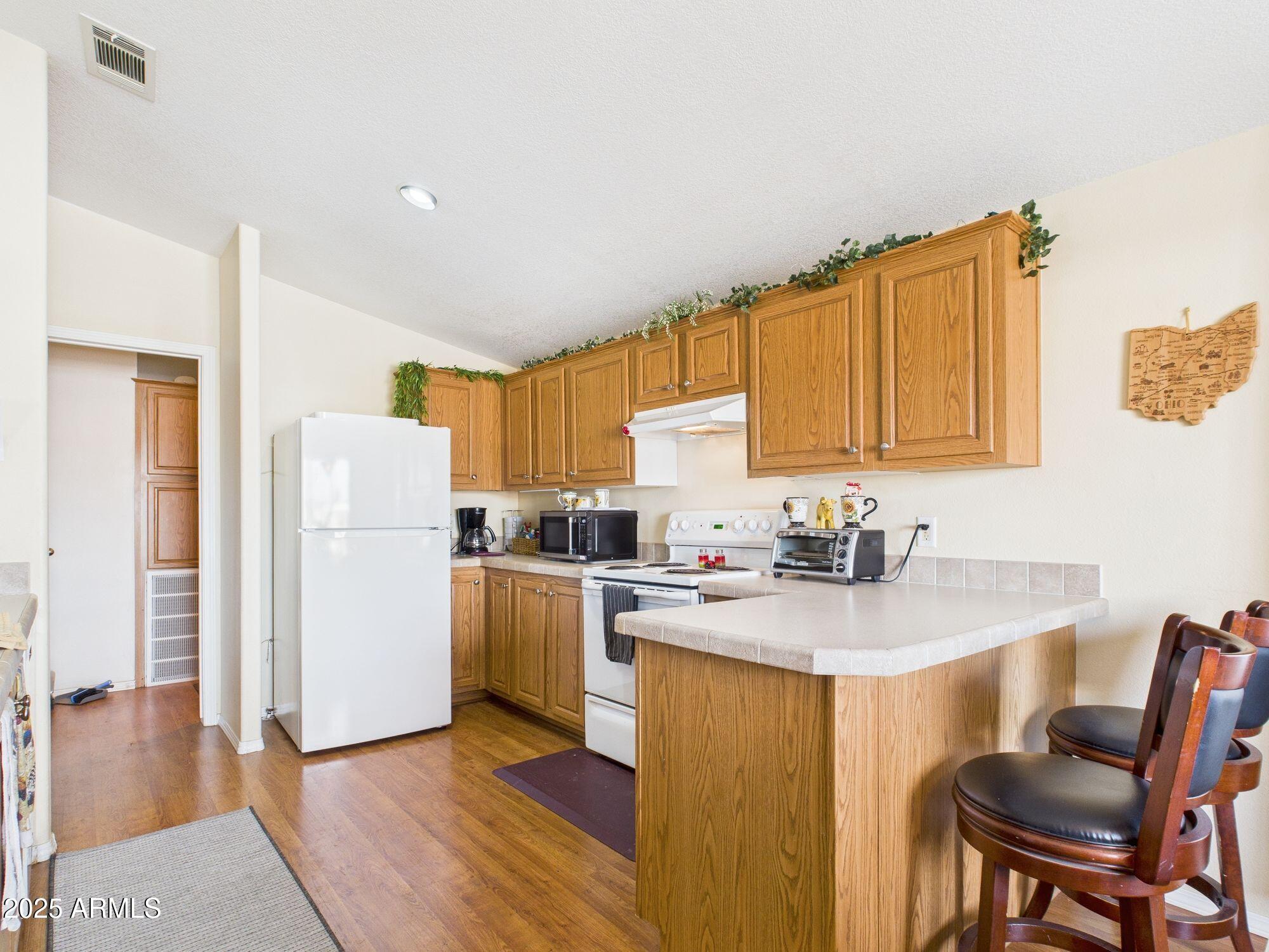3104 East Broadway Road, Unit 230 Mesa, AZ 85204 - Photo 9 of 24 a kitchen with a sink a stove cabinets and wooden floor