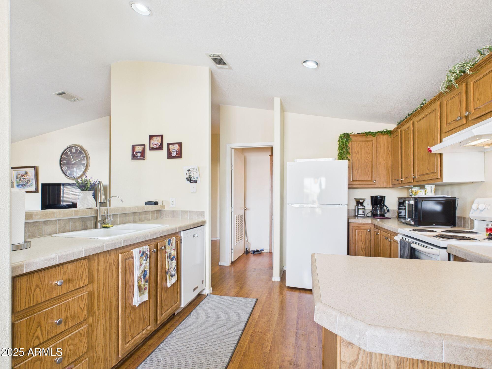 3104 East Broadway Road, Unit 230 Mesa, AZ 85204 - Photo 10 of 24 a large kitchen with stainless steel appliances a large counter top a stove a sink dishwasher and a refrigerator