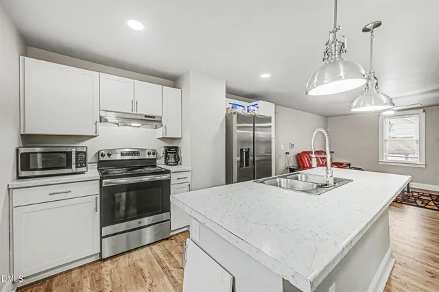 a kitchen with stainless steel appliances kitchen island a sink refrigerator and cabinets