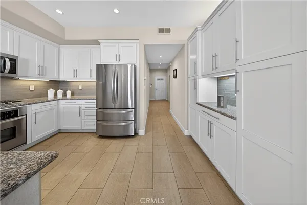 a kitchen with stainless steel appliances granite countertop wooden floor a dining table and chairs