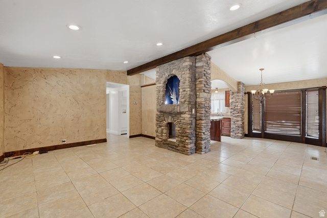 2875 North Hill Field Road, Unit 111 Layton, UT 84041 - Photo 3 of 30 Unfurnished living room with arched walkways, vaulted ceiling with beams, a chandelier, and light tile patterned floors