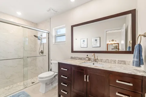 a bathroom with a granite countertop sink toilet and shower
