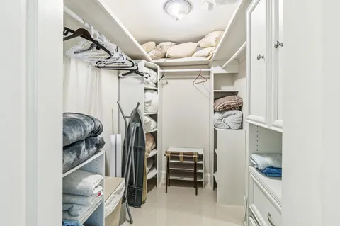 a view of walk in closet with clothes and shoes