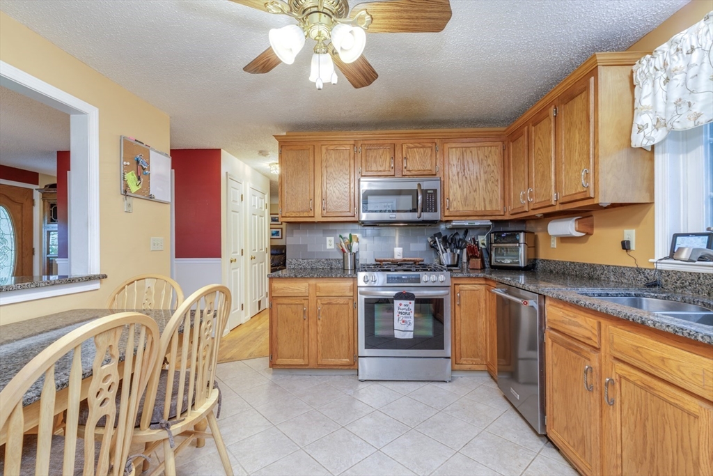 50 Kienia Road Hudson, NH 03051 - Photo 10 of 42 a kitchen with stainless steel appliances granite countertop a sink a stove cabinets dining table and chairs