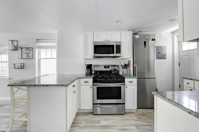 a kitchen with stainless steel appliances granite countertop a stove a refrigerator and a microwave