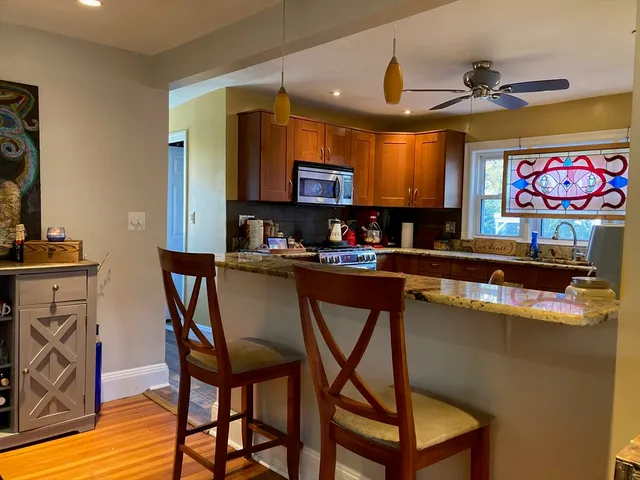 a kitchen with stainless steel appliances granite countertop a stove top oven a sink a dining table and chairs with wooden floor