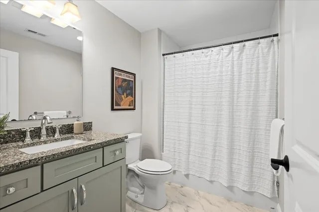 a bathroom with a granite countertop toilet sink and mirror