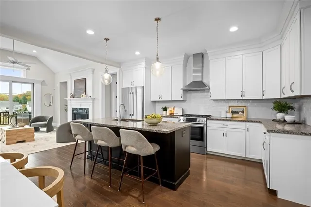 a kitchen with stainless steel appliances granite countertop a table chairs stove and white cabinets