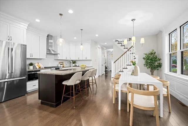a kitchen with stainless steel appliances kitchen island granite countertop a table chairs and a refrigerator
