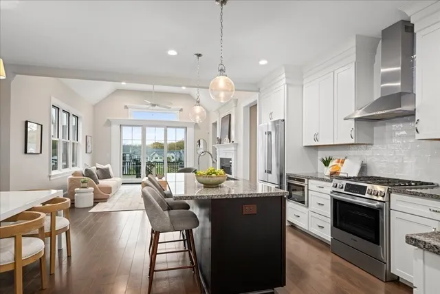 a kitchen with stainless steel appliances granite countertop a stove top oven a sink dishwasher a dining table and chairs with wooden floor